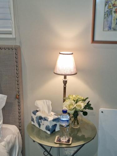 uma mesa com um candeeiro e uma garrafa de água e flores em Haven Sanctuary Suite with Private Entrance em Queenstown