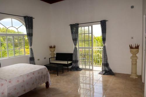 a bedroom with a bed and a couch and windows at Kokojo Villa in Black River