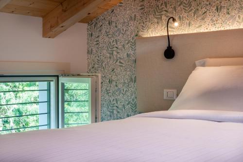 een slaapkamer met een wit bed en een raam bij BORGO STALIS RESORT in Sesto al Reghena