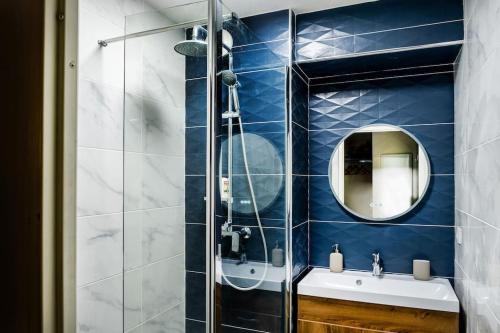 La salle de bains est pourvue de carrelage bleu, d'un lavabo et d'un miroir. dans l'établissement Lourde center Apartment 3 bed with Parking, à Lourdes