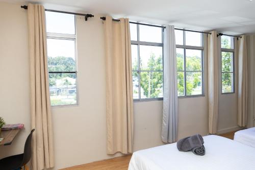 a bedroom with three windows and a white bed at Familia Motel Kangar in Kangar