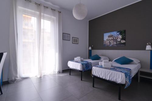 a bedroom with two beds and a large window at B&B Le Porte Del Centro in Palermo