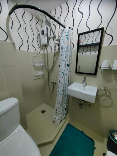 a bathroom with a toilet and a sink and a mirror at Casa Felicitas 2 - Home Feels 2 Bdr Condo Unit at Seawind Condominium in Davao City