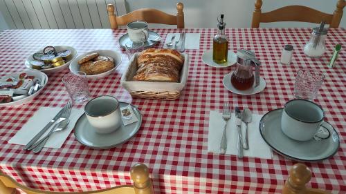 a table with a red and white checkered table cloth with food and coffee at Casa rural La Colmena del Geoparque TR -CC 00489 in Navatrasierra
