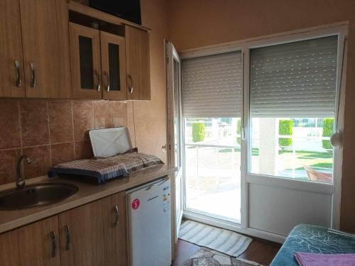 a kitchen with a sink and a sliding glass door at Krapce - Lake View Apartments in Star Dojran