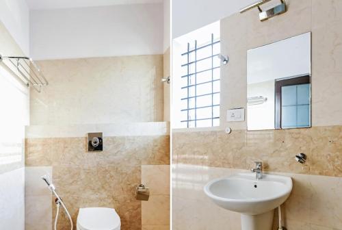 W łazience znajduje się umywalka, toaleta i lustro. w obiekcie The Hillside Hotel w mieście Mysuru