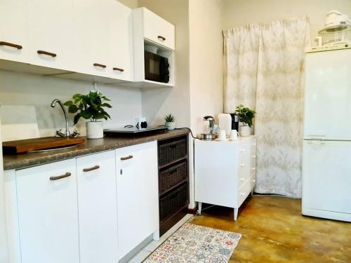 a kitchen with white cabinets and a white refrigerator at Firefly Cottage: Cosi nest tucked away in garden in Kenton on Sea