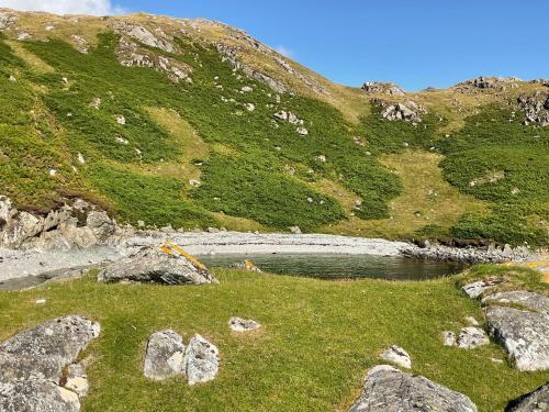 a hillside with a body of water and some rocks at 6 Calbost in Calbost