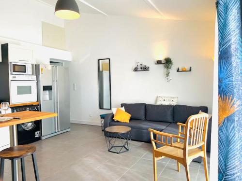 sala de estar con sofá azul y cocina en Appartement Le Cosy de La Ramée, en Tournefeuille