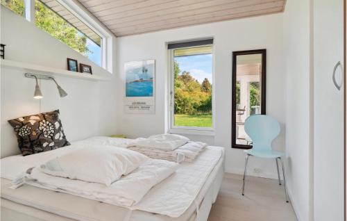 two beds in a white bedroom with a blue chair at 3 Bedroom Cozy Home In Sjællands Odde in Yderby