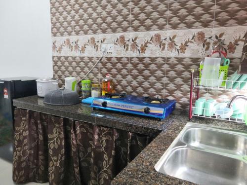a kitchen counter with a sink and a appliance on it at Mira Homestay Gurun - Pendang in Pendang