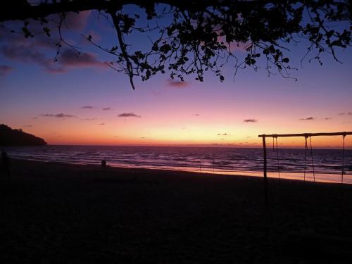 a sunset on the beach with a swing at Tumombuvoi Homestay (Sidi place) in Tiga Papan