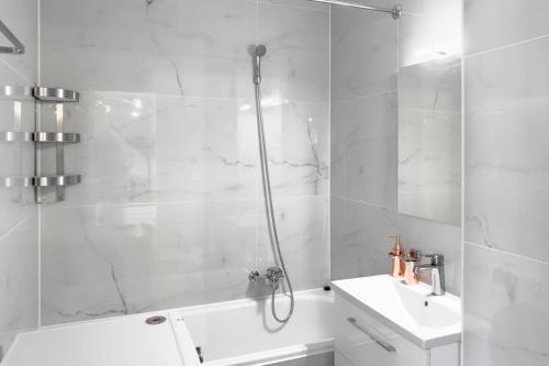 La salle de bains blanche est pourvue d'une douche et d'un lavabo. dans l'établissement Panoramic Garden Studio, à Veytaux