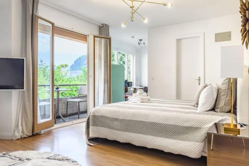 a white bedroom with a large bed and a balcony at Panoramic Garden Studio in Veytaux