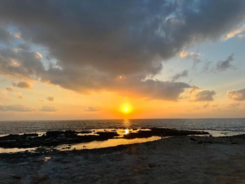 Vacation Apartment by The Sea - Achziv في نهاريا: غروب الشمس على المحيط مع غروب الشمس