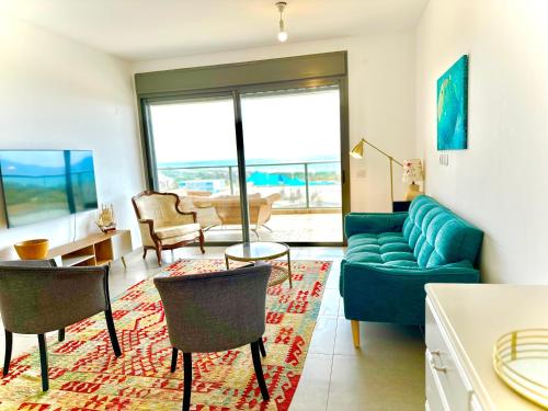 sala de estar con sofá azul y sillas en Vacation Apartment by The Sea - Achziv, en Nahariyya