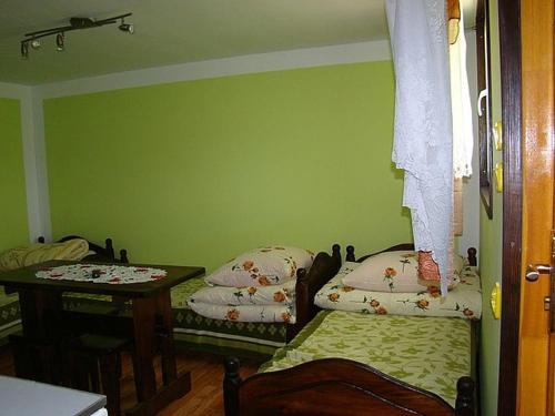 a green room with two beds and a table at Domek nr8 in Zawóz