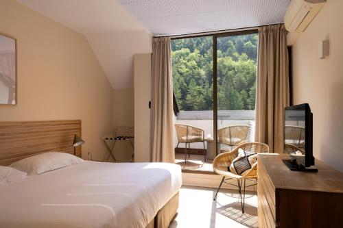 une chambre avec un lit et une grande fenêtre dans l'établissement Hôtel de la Muse et du Rozier, à Mostuéjouls