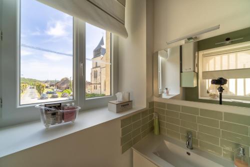 uma casa de banho com um lavatório e uma janela em Le Clos de la Tour 
