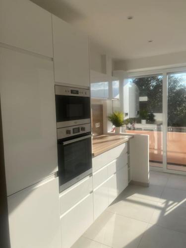 une cuisine avec des armoires blanches et un four à plaques de cuisson dans l'établissement Appartement T3 porto vecchio, à Porto-Vecchio