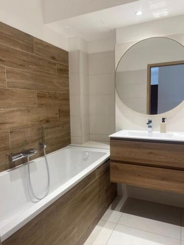une salle de bain avec une baignoire, un lavabo et un miroir dans l'établissement Appartement T3 porto vecchio, à Porto-Vecchio
