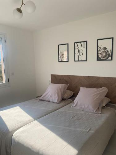- 2 lits dans une chambre avec des photos sur le mur dans l'établissement Appartement T3 porto vecchio, à Porto-Vecchio