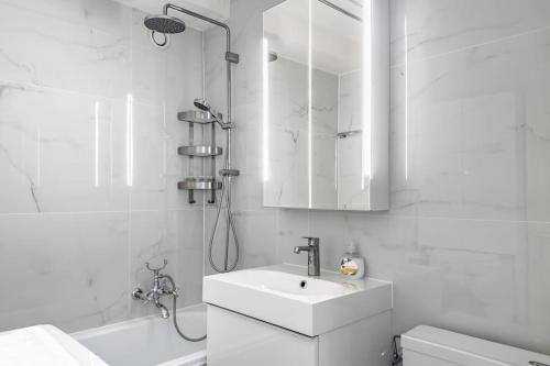 La salle de bains blanche est pourvue d'un lavabo et d'une douche. dans l'établissement Mountain Sunrise Studio, à Veytaux
