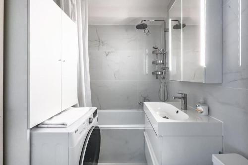 La salle de bains blanche est pourvue d'un lavabo et d'un lave-linge. dans l'établissement Mountain Sunrise Studio, à Veytaux