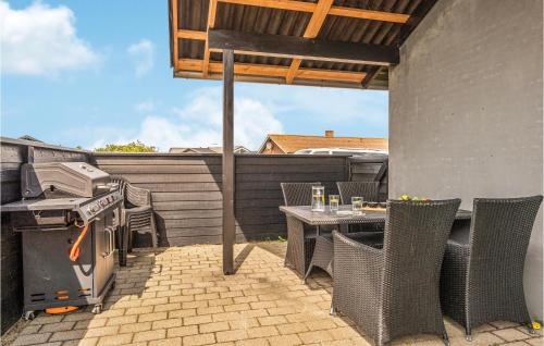 an outdoor patio with a grill and a table and chairs at 3 Bedroom Amazing Home In Hvide Sande in Havrvig