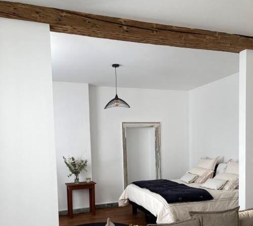 a white bedroom with a bed and a mirror at Un Petit Château in Lauzun