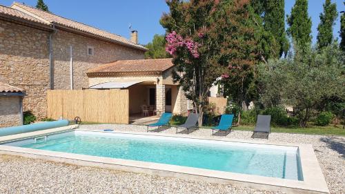 une piscine avec des chaises et une maison dans l'établissement La Maison d'Isidore - Gîte 6 personnes avec climatisation, piscine et jardin clos, à Saint-Victor-la-Coste