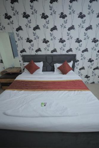 a bed with white sheets and red pillows in a bedroom at Hotel Mukund Dham-Near Mathura Railway Station in Mathura
