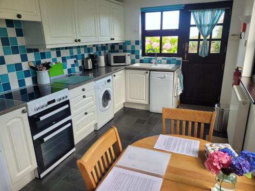 a kitchen with white cabinets and a wooden table at Long Linhay in Woolacombe