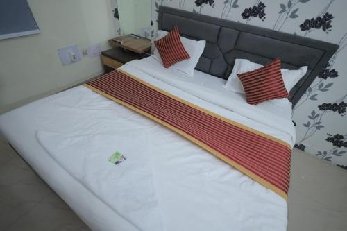 a bed with white sheets and red pillows at Hotel Mukund Dham-Near Mathura Railway Station in Mathura