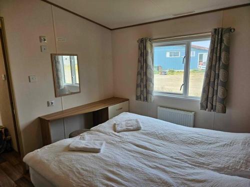 um quarto com uma cama com duas toalhas em End of the road Farm-Cabin em Búðardalur