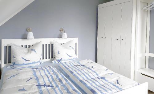 a white bedroom with a bed with blue and white pillows at Schöner Blick 