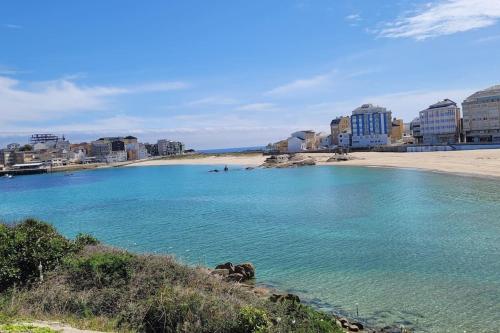 een strand met gebouwen en een zandstrand bij Piso con vistas al mar. Apartamento Miramar in San Cibrao