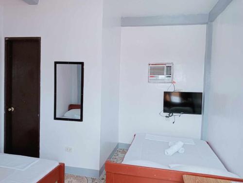 um quarto branco com um espelho e uma cama em Ludy's 2 Pension House em Carles