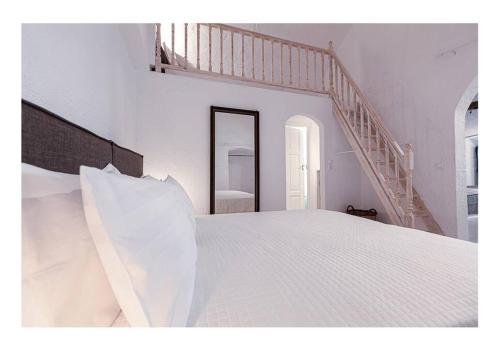 a white bedroom with a white bed and a staircase at Apanemo seaside house in Spetses
