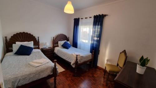 a bedroom with two beds and a table and a window at Zinha's Guest House in Moledo