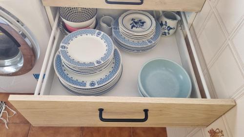 a drawer full of plates and bowls in a cabinet at Zinha's Guest House in Moledo