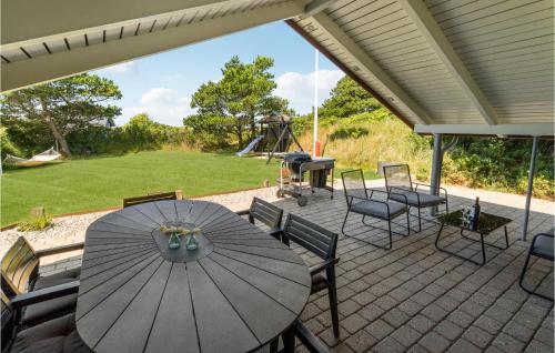 a patio with a table and chairs and a playground at Holiday Home Ringvejen X in Lakolk