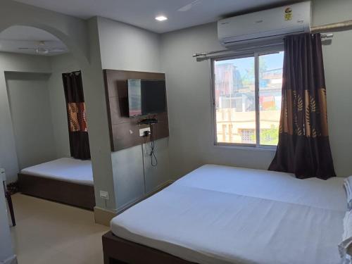 ein Schlafzimmer mit zwei Betten und einem Fernseher und einem Fenster in der Unterkunft Kusum Hotel in Dibrugarh