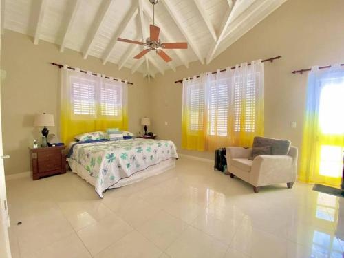 a bedroom with a bed and a chair and a ceiling fan at Tranquil Townhome, close to beach & dining in Saint James
