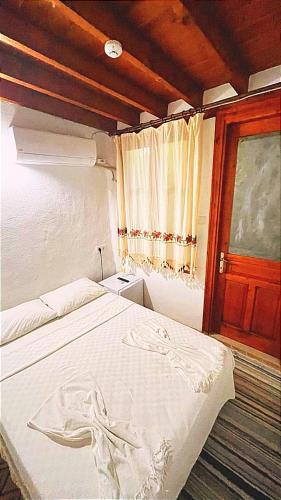 um quarto com uma cama branca e uma janela em Ayvalık Aygün pansiyon em Ayvalik