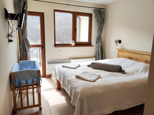 a bedroom with a bed and a chair and windows at Терасите - Къща 4 in Ribarica