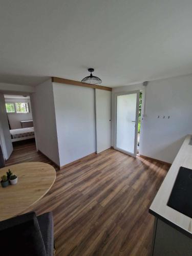 ein leeres Wohnzimmer mit Holzboden und einem Tisch in der Unterkunft Appartement avec terrasse in La Talaudière