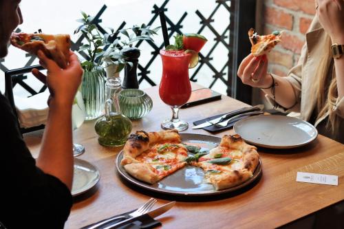 two people sitting at a table eating pizza at Apartamenty Chełmińskie in Chełmno