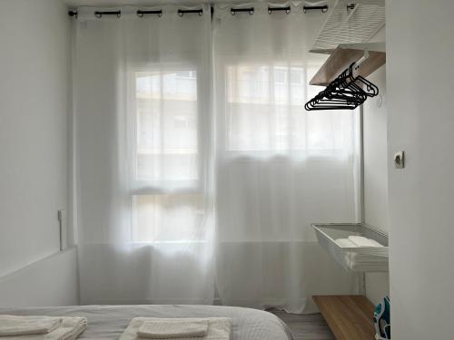 Schlafzimmer mit einem Bett und einem Fenster mit weißen Vorhängen in der Unterkunft Appart Cozy CDG, Paris, Disney, Parc Expo, Astérix in Dammartin-en-Goële