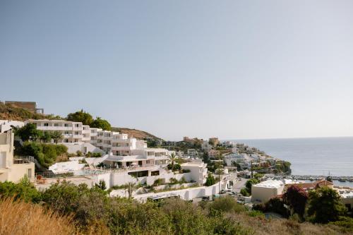 a cluster of white buildings on a hill next to the ocean at Bali Beach and Sofia Village in Balíon